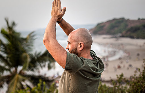 hombre juntando las palmas de sus manos en la playa