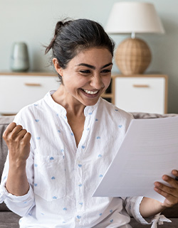 mujer feliz mientras lee informacion de una hoja de papel