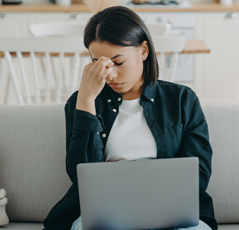 mujer con dolor en su rostro mientras usa portatil