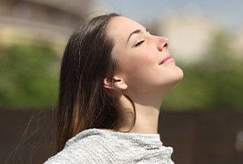 mujer con los ojos cerrados respirando al aire libre