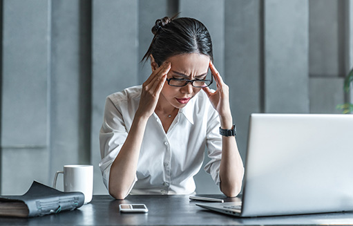 mujer con computador tiene dolor de cabeza