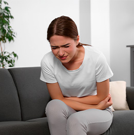 mujer sentada en el sofa sufre por dolor de estomago