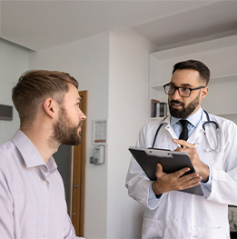 hombre mirando a doctor quien lleva una lista en la mano