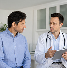 hombre conversa con medico en consulta